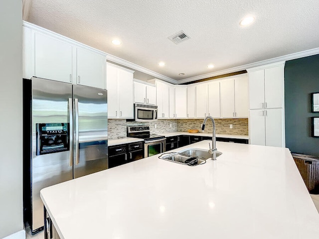 kitchen featuring white cabinets, sink, a textured ceiling, ornamental molding, and appliances with stainless steel finishes