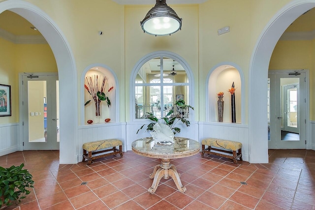 tiled foyer with ornamental molding and a high ceiling