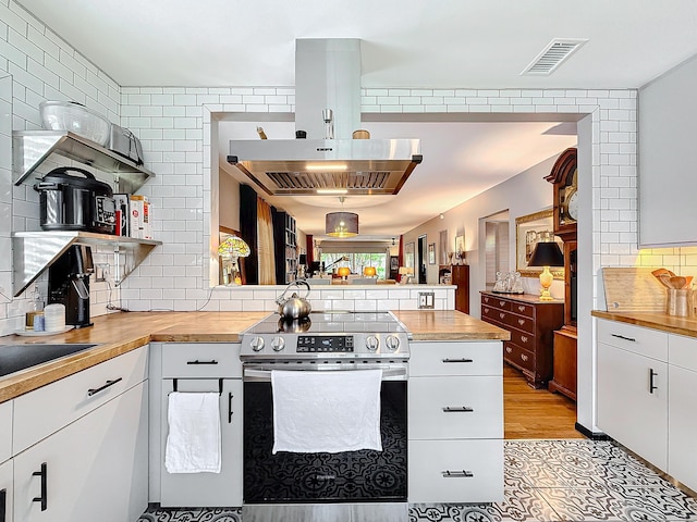 533 SE 28th Cir Unit 533, Boynton Beach, FL 33435 - kitchen featuring stainless steel range with electric stovetop, butcher block counters, a peninsula, decorative backsplash, and open shelves