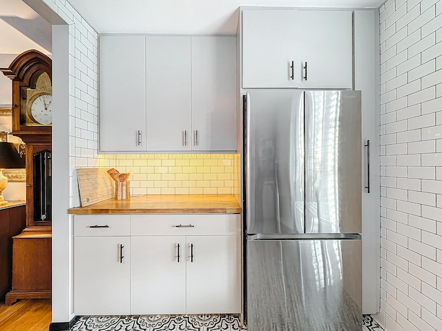 kitchen with wooden counters, stainless steel fridge, light hardwood / wood-style flooring, and white cabinetry