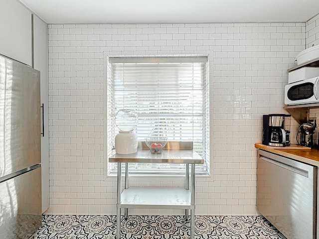 kitchen featuring appliances with stainless steel finishes, breakfast area, tile walls, and light tile patterned flooring