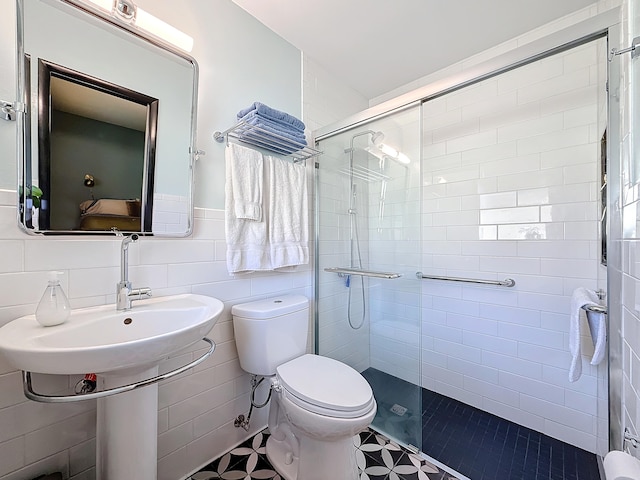 bathroom with an enclosed shower, tile patterned floors, toilet, and tile walls