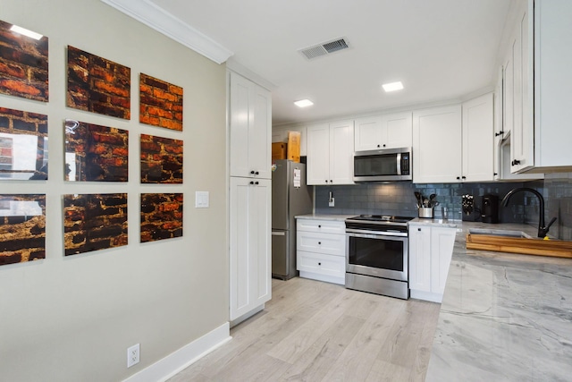 kitchen with visible vents, a sink, backsplash, appliances with stainless steel finishes, and white cabinets