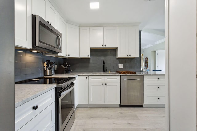 kitchen featuring a sink, white cabinets, light stone countertops, and stainless steel appliances