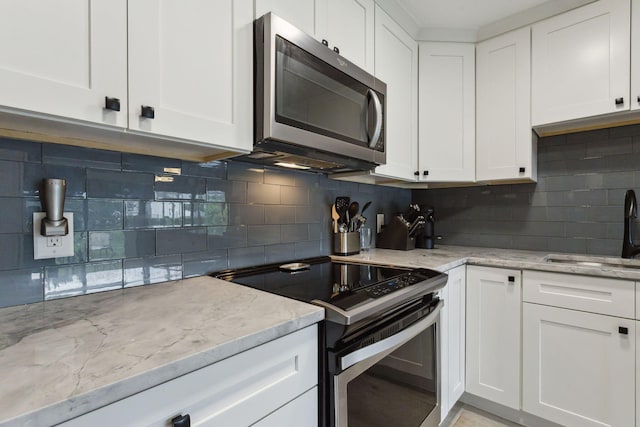 kitchen with stainless steel microwave, electric range, white cabinets, and a sink