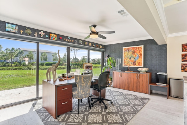 office area with visible vents, wallpapered walls, light wood-style flooring, ceiling fan, and crown molding