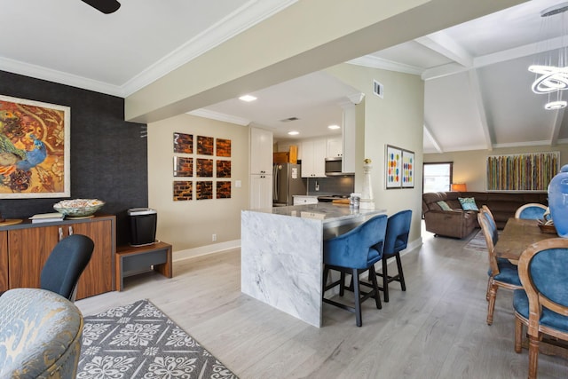 kitchen featuring appliances with stainless steel finishes, a kitchen bar, light hardwood / wood-style floors, white cabinets, and kitchen peninsula