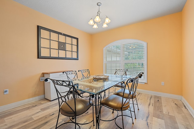 dining space featuring a chandelier, a textured ceiling, and light hardwood / wood-style flooring