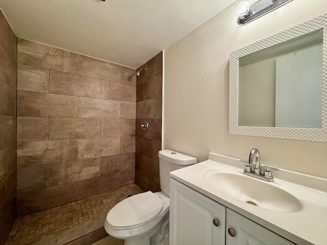 bathroom with a tile shower, vanity, and toilet