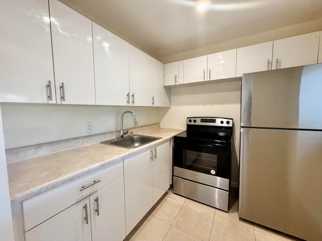 kitchen with white cabinetry, sink, light tile patterned floors, and stainless steel appliances