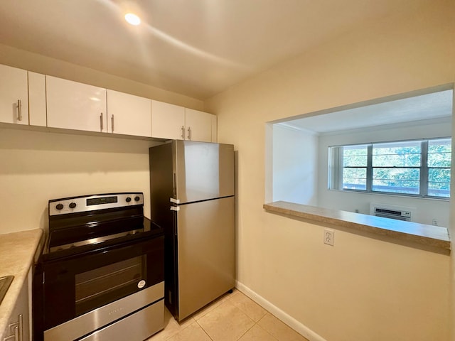 kitchen with a wall mounted air conditioner, appliances with stainless steel finishes, light tile patterned floors, and white cabinets