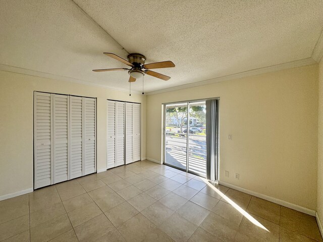 206 Dorchester Unit I, West Palm Beach, FL 33417 - unfurnished bedroom featuring crown molding, two closets, access to outside, baseboards, and a textured ceiling