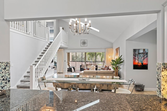 interior space featuring dark stone countertops, hanging light fixtures, high vaulted ceiling, and a chandelier