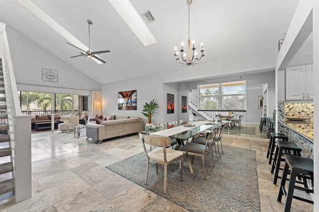 dining space with plenty of natural light, ceiling fan with notable chandelier, and high vaulted ceiling