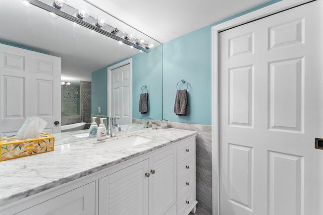 bathroom featuring a shower, vanity, and tile walls