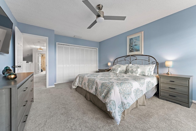 carpeted bedroom featuring ceiling fan, a textured ceiling, and a closet