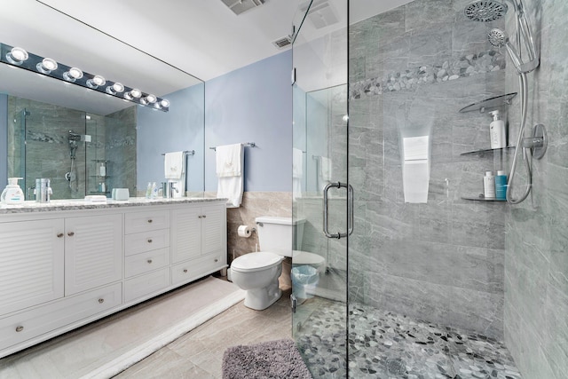 bathroom featuring vanity, a shower with shower door, tile walls, and toilet