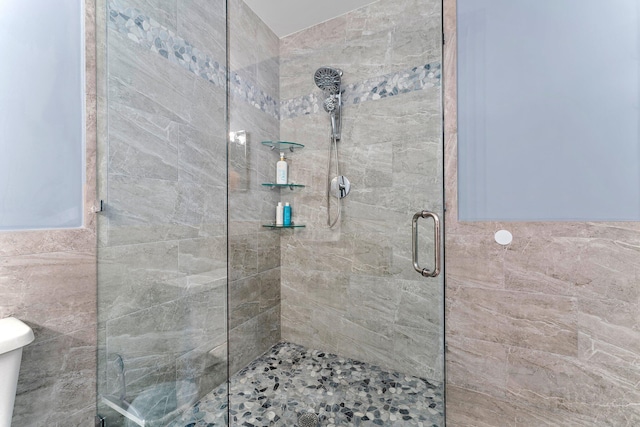 bathroom featuring a shower with door and tile walls