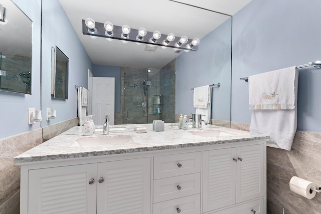 bathroom featuring vanity, a shower with shower door, and tile walls