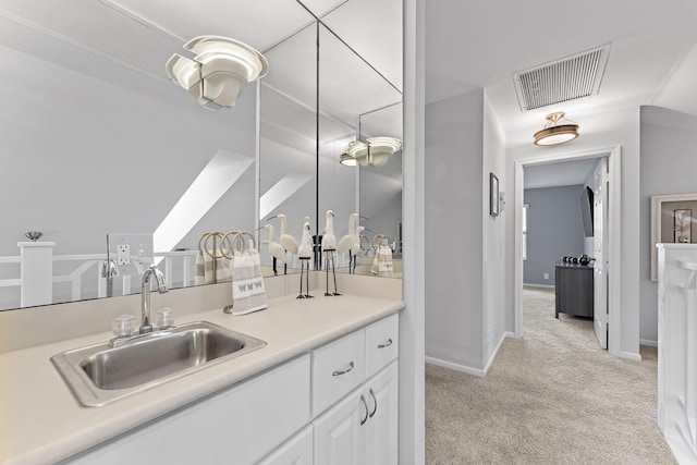 kitchen with light colored carpet, white cabinetry, and sink