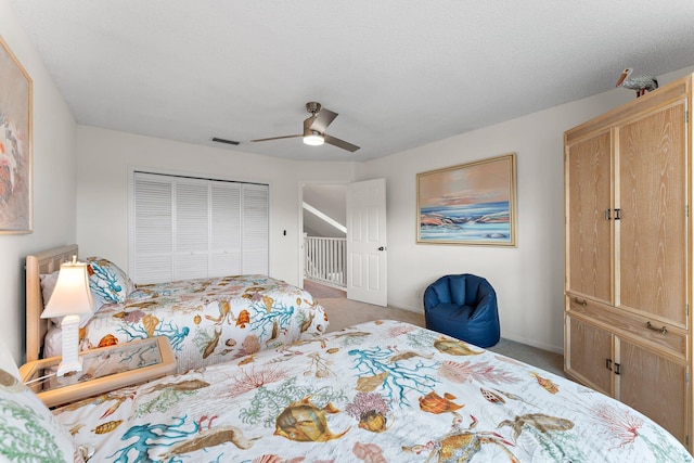 bedroom with ceiling fan, a closet, light colored carpet, and a textured ceiling