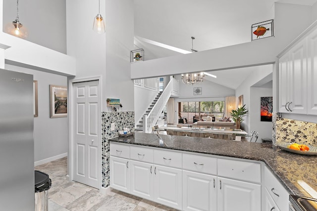 kitchen with white cabinets, appliances with stainless steel finishes, backsplash, and hanging light fixtures