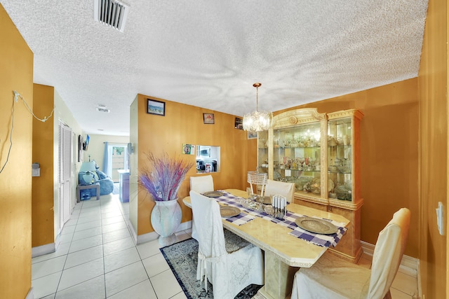 tiled dining space with a notable chandelier and a textured ceiling