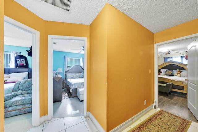 hallway featuring a healthy amount of sunlight, light hardwood / wood-style floors, and a textured ceiling