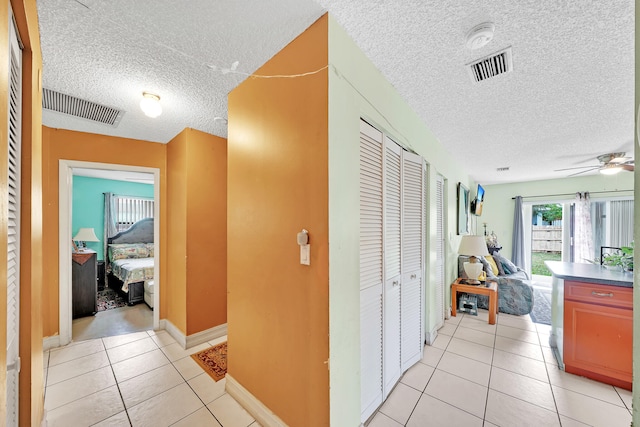 corridor featuring a textured ceiling and light tile patterned flooring