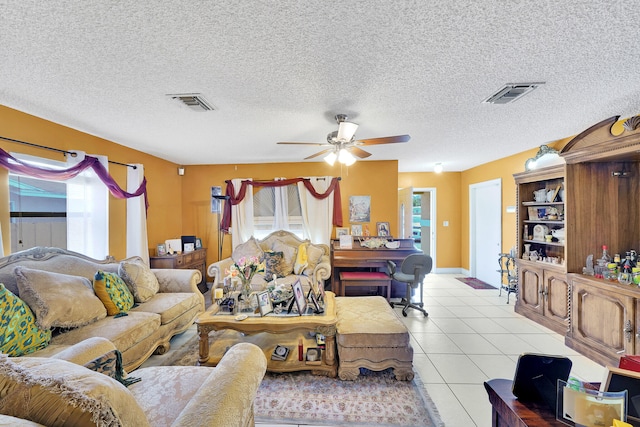 living room featuring ceiling fan, light tile patterned floors, and a textured ceiling