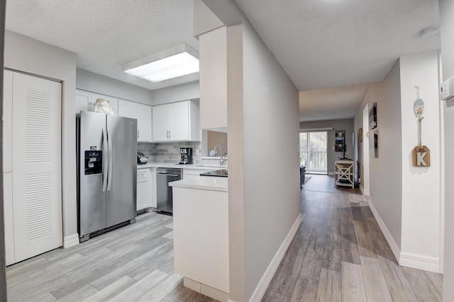 kitchen featuring sink, appliances with stainless steel finishes, white cabinetry, tasteful backsplash, and light wood-type flooring