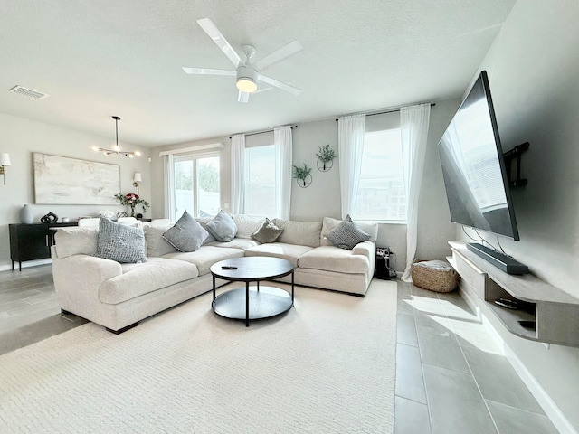 living room featuring ceiling fan with notable chandelier and light tile patterned flooring