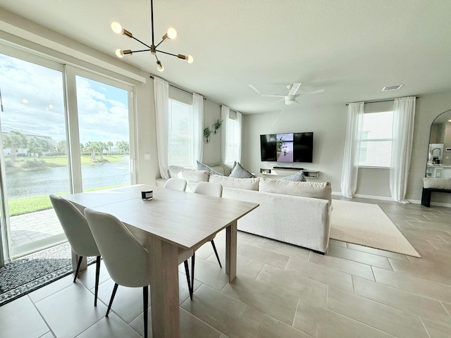 tiled dining area with a water view and ceiling fan with notable chandelier