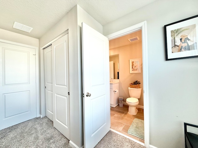 bathroom with tile patterned flooring, a textured ceiling, and toilet