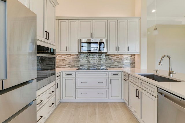 kitchen featuring white cabinets, sink, tasteful backsplash, light hardwood / wood-style floors, and stainless steel appliances