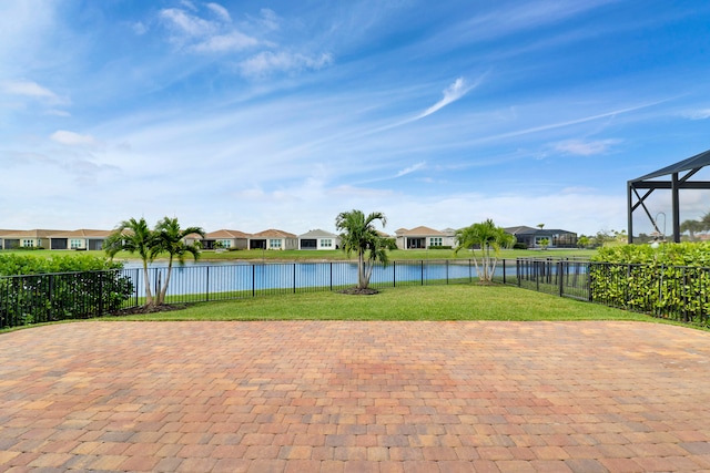 view of swimming pool featuring glass enclosure, a water view, and a yard