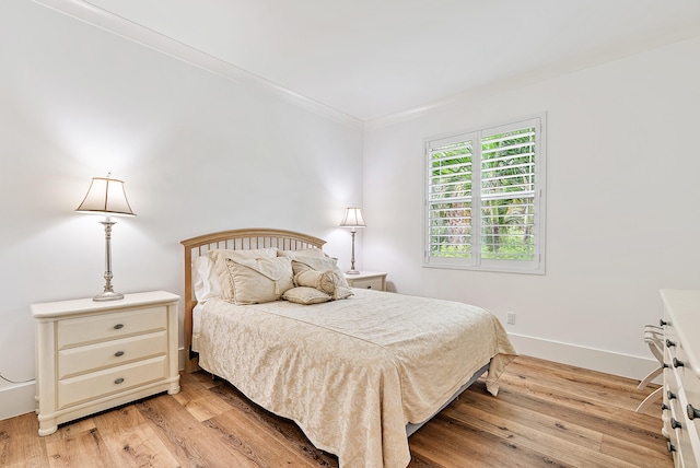 bedroom with ornamental molding and light hardwood / wood-style floors