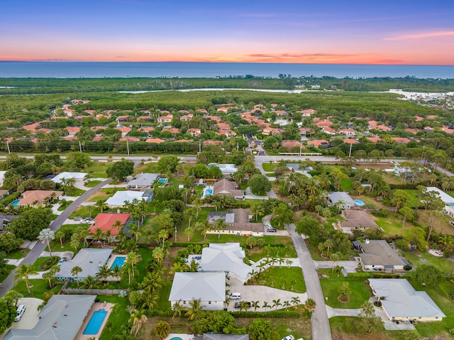 aerial view at dusk featuring a water view