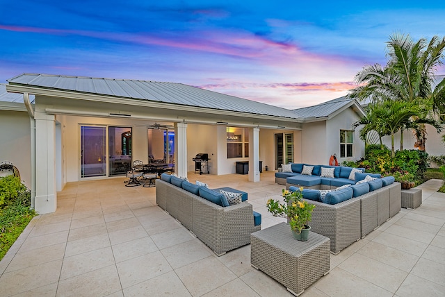 patio terrace at dusk with area for grilling, ceiling fan, and an outdoor hangout area