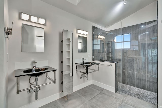 bathroom with tile patterned flooring, a tile shower, sink, and vaulted ceiling