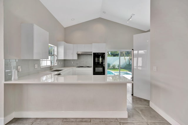 kitchen featuring sink, kitchen peninsula, black double oven, decorative backsplash, and white cabinets