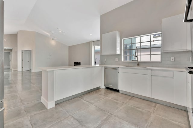 kitchen with decorative backsplash, stainless steel dishwasher, sink, white cabinets, and lofted ceiling