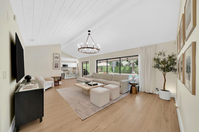 living room featuring a chandelier, lofted ceiling with beams, and light wood-type flooring