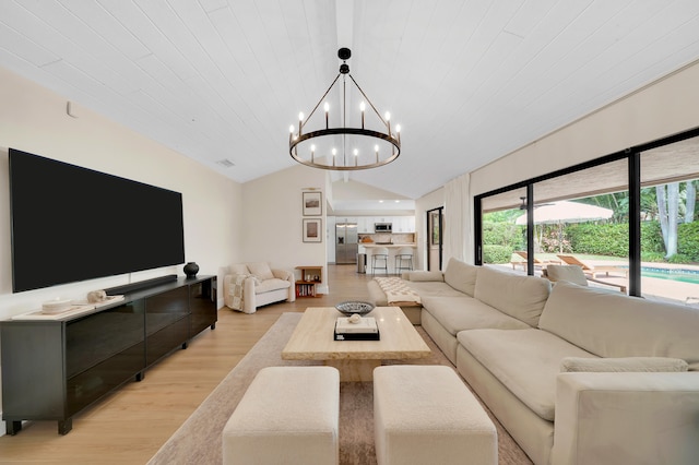 living room featuring light wood-type flooring, an inviting chandelier, and vaulted ceiling