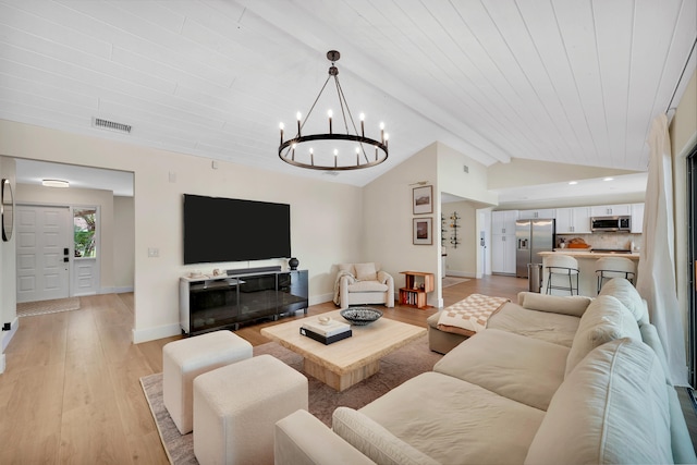 living room with vaulted ceiling with beams, a chandelier, and light wood-type flooring