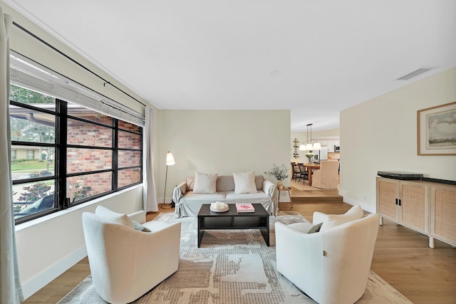 living room featuring light hardwood / wood-style flooring, a wealth of natural light, and a notable chandelier