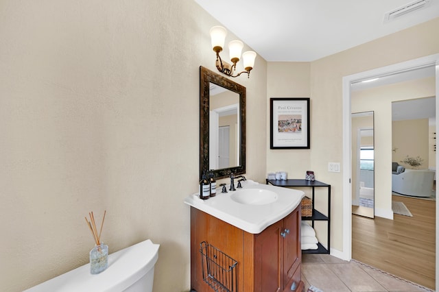 bathroom with hardwood / wood-style floors, vanity, an inviting chandelier, and toilet