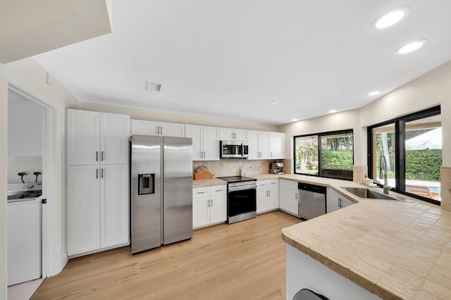 kitchen featuring white cabinets, appliances with stainless steel finishes, light wood-type flooring, and sink