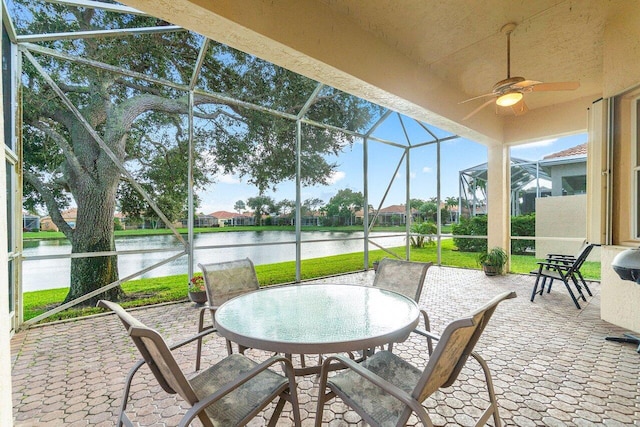 view of patio featuring a water view, glass enclosure, and ceiling fan