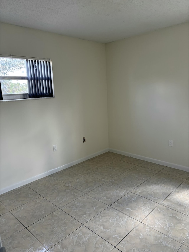 tiled empty room with a textured ceiling